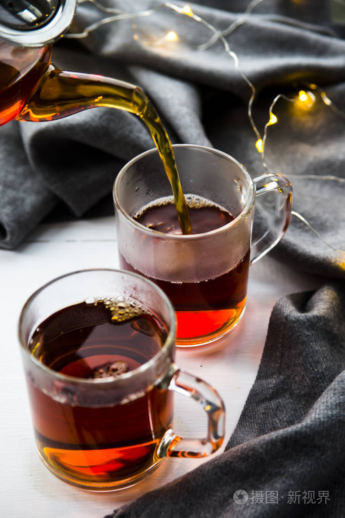 将红茶从透明的茶壶倒入杯中冬季家居理念