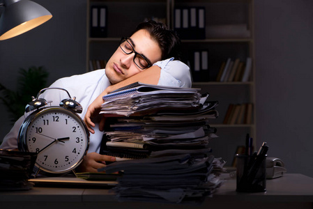 加班时钟年轻的生意人加班工作到深夜照片