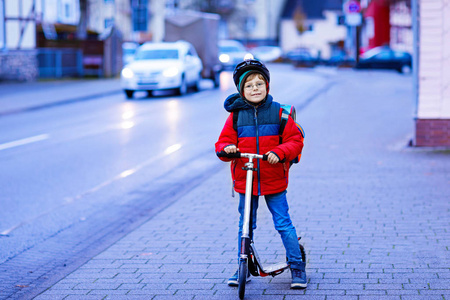 可爱的小男孩骑着滑板车在上学的路上