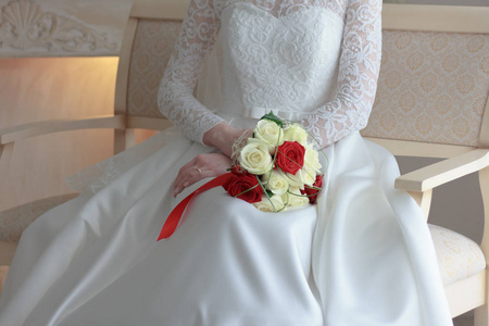 新娘在白色婚纱礼服坐和举行婚礼花束