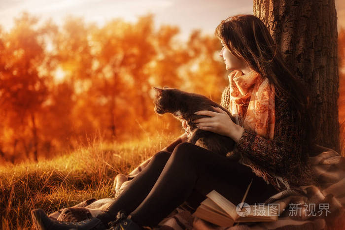 女孩和一只猫在片秋色的公园