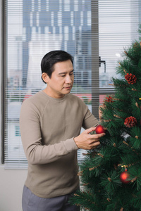 庆祝新年。亚洲男子站在新圣诞树在家里