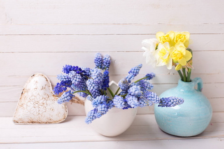 蓝色的 muscaries 和黄水仙花花瓶及装饰心白色木制背景上。文本的地方。选择性的焦点