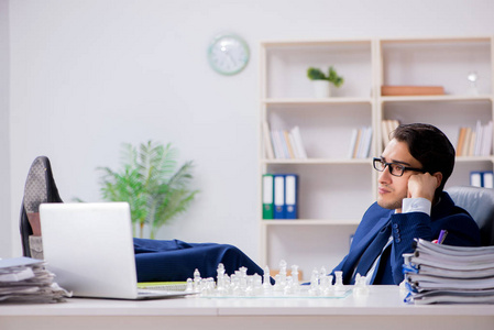 年轻生意人在办公室里玩玻璃象棋