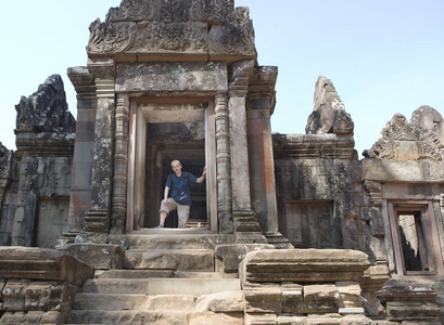 该名男子在古毁坏寺庙的台阶上的游客。暹粒, Cambodi