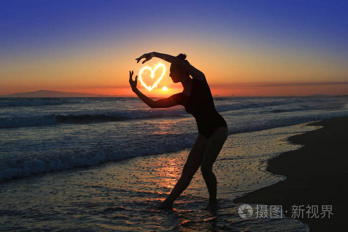 日落时在海滩的熟练的年轻舞蹈家