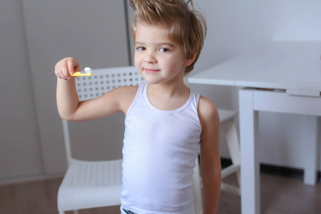 滑稽的小男孩站立用牙刷为清洁他的牙