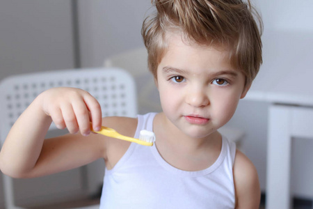 滑稽的小男孩站立用牙刷为清洁他的牙