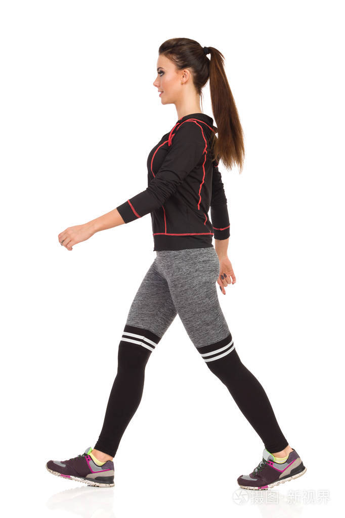 穿着运动服和条纹紧身裤的年轻女性微笑.侧面视图