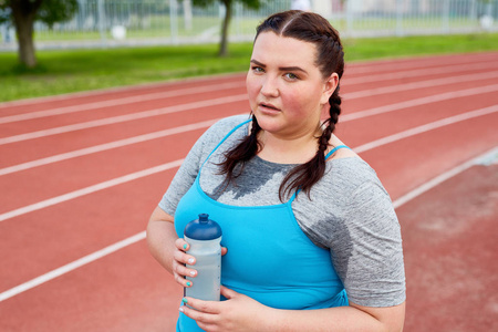 出汗的肥胖妇女与一瓶水有短休息之间锻炼套