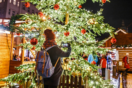 在除夕夜, 在欧洲城市的主要广场上欣赏圣诞树和灯光的女游客