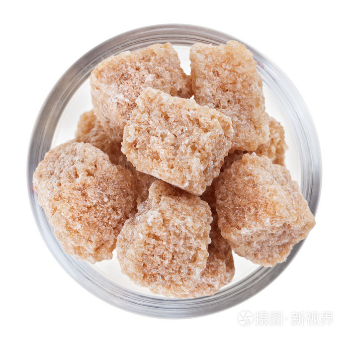 brown lump cane sugar in a glass bowl, isolated on white