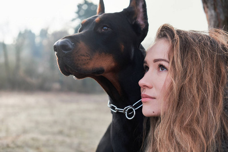 美丽的年轻女子与她的杜宾狗的肖像.暖色自然颜色照片