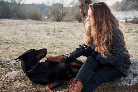 美丽的年轻女子与她的杜宾狗的肖像。暖色自然颜色
