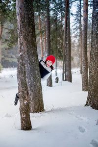 女孩在一个红色盖帽和温暖的夹克在森林在冬天