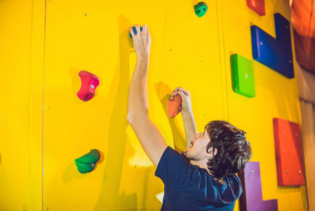 男子攀岩抱石健身房在人工攀岩墙上
