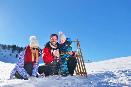 幸福年轻的家庭，在新鲜的雪打美丽晴朗的冬日户外性质