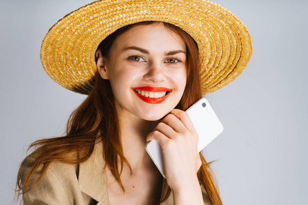 滑稽的女孩在帽子和用红色嘴唇笑和拿着电话