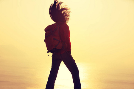 有背包的少妇站立在日出风的海岸