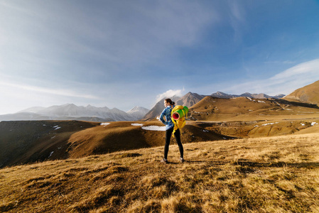 一个穿着蓝色夹克的年轻活泼的女孩沿着高加索山脊旅行, 享受大自然和清新的空气