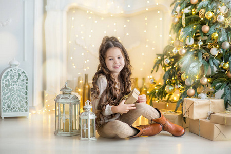 儿童礼品盒圣诞树和壁炉在家附近的小女孩