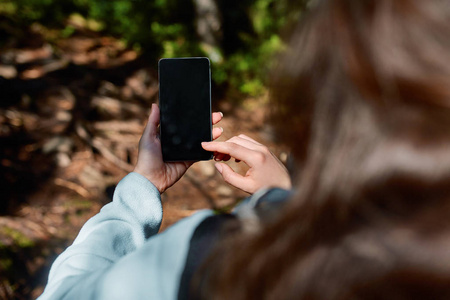 女孩手持空屏手机在雨林花园