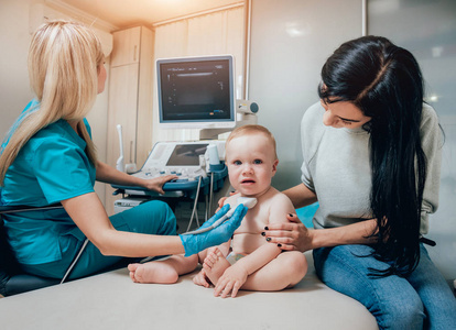 医生和婴儿女孩与母亲在超声诊断。医疗设备。超声