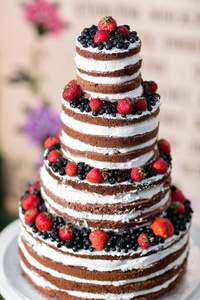 圆的多层次婚礼蛋糕与海绵, 奶油, 果酱和浆果的圆形基地。新鲜的蓝莓和草莓