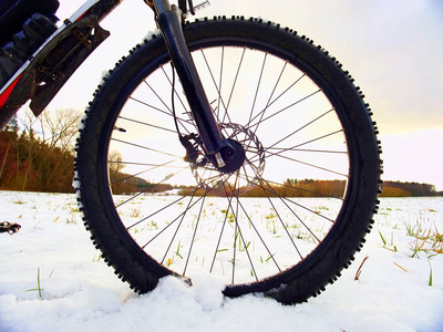 山地自行车前轮留在雪地里。雪片在漆黑的路上轮胎融化