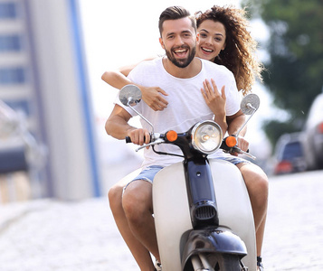 快乐的年轻夫妇，在晴朗的一天骑摩托车在城市