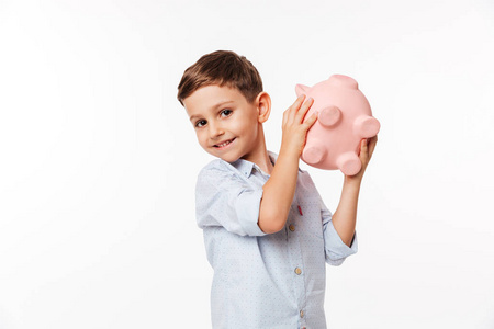 一个快乐可爱的小男孩的肖像持有小猪银行
