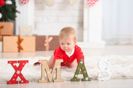 可爱的婴儿在圣诞老人的服装和字圣诞节在地板上在家里