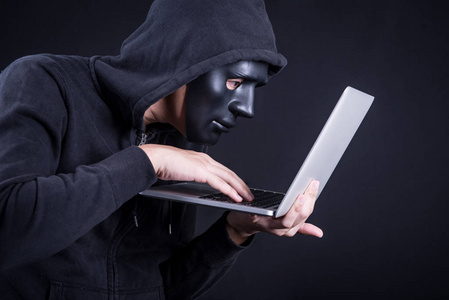 戴着黑色面具携带笔记本的男性黑客