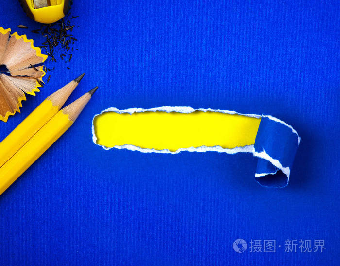 一支黄色铅笔在撕裂的蓝色纸和空间为文本与叶