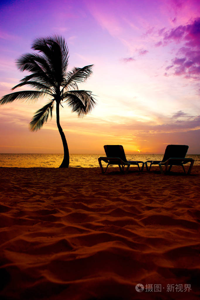 美丽的日出在海洋海岸, 棕榈树和太阳躺椅