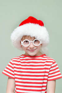 可爱的男孩戴着圣诞老人的帽子, 戴着眼镜微笑。肖像