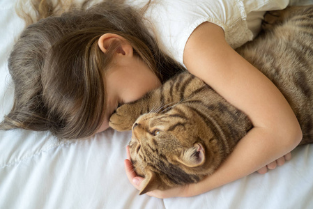 小女孩抚摸猫躺在床上