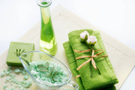 水疗套装 液体肥皂海盐绿色毛巾鲜花白色背景的旧黄餐巾上的橄榄树叶