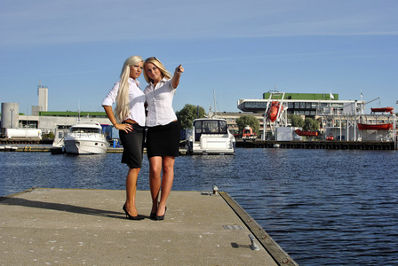 两个金发女孩站在码头上，手指一指