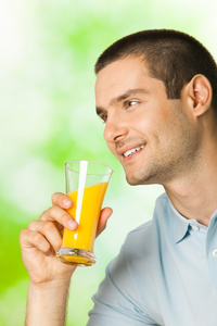 年轻快乐微笑的男人喝橙汁胜过