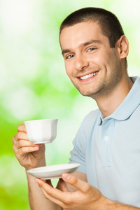 年轻快乐微笑的男人在户外喝咖啡的画像