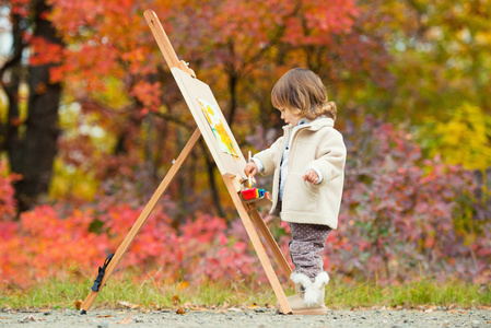 秋天的女婴画在秋叶公园, 小孩画画, 孩子们的创造力照片