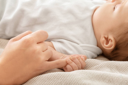 婴儿抱着妈妈的手在床上