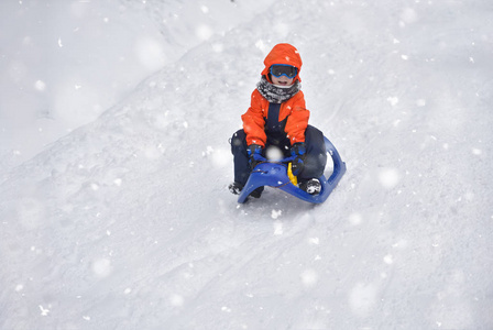 冬天的时候, 小男孩在雪地上滑行