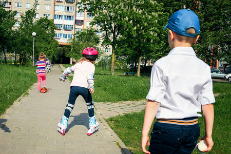 那女孩在街上学滑冰。儿童佩戴防护垫和防护头盔, 安全地骑在滚筒上。积极开展儿童体育活动