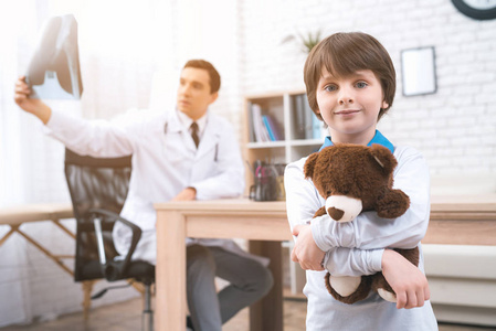一个小男孩站在医疗室的泰迪熊