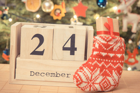 复古相片, 日期12月24日在日历, 礼物在袜子和圣诞树与装饰, 平安夜时间