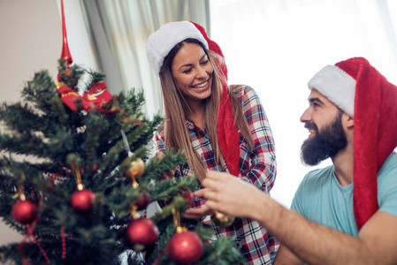 年轻夫妇装饰一棵圣诞树