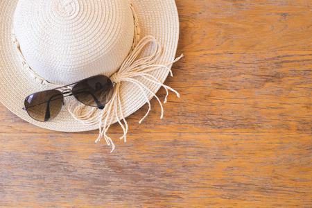木制背景下戴着太阳眼镜的草帽