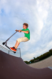 男孩用他的滑板车在空中跳跃图片